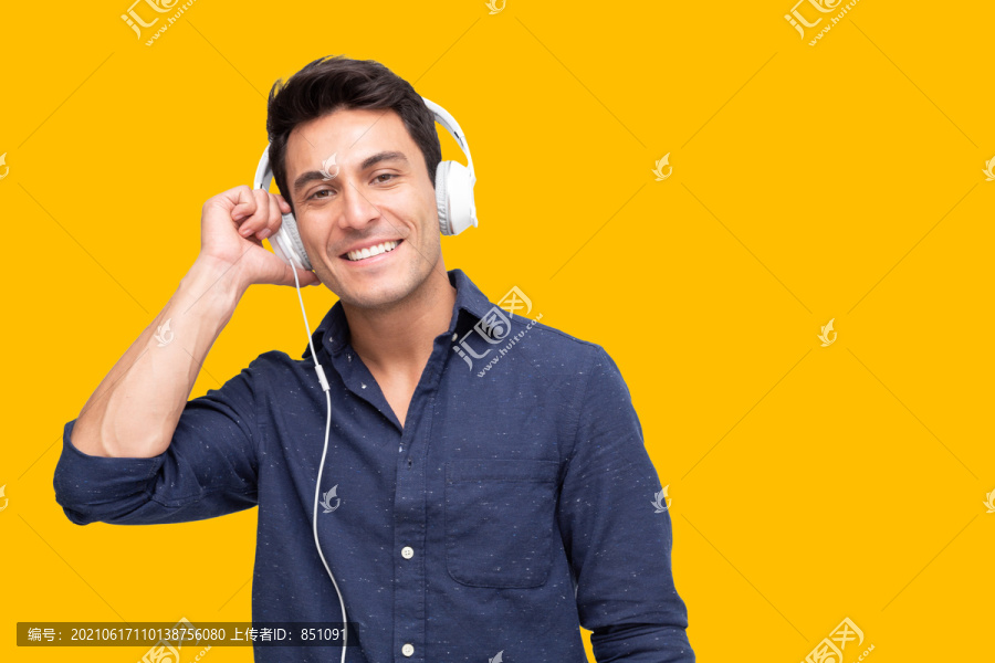 年轻人在播放列表歌曲应用程序中用耳机听音乐，黄色背景上隔离