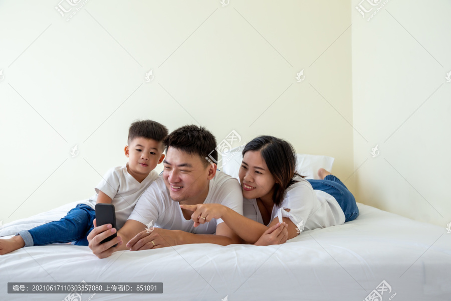 快乐的亚洲小家庭用智能手机、爸爸、妈妈和儿子在手机上进行自拍