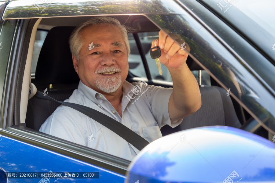 亚洲高级男子司机微笑着展示新车钥匙，坐在车内