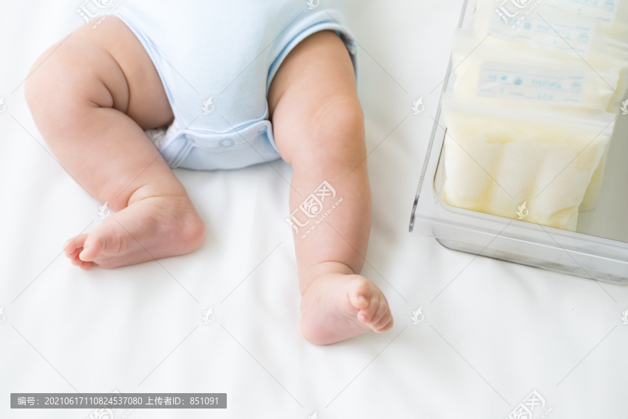 储存袋中冷冻的母乳和躺在白色床上的腿部婴儿