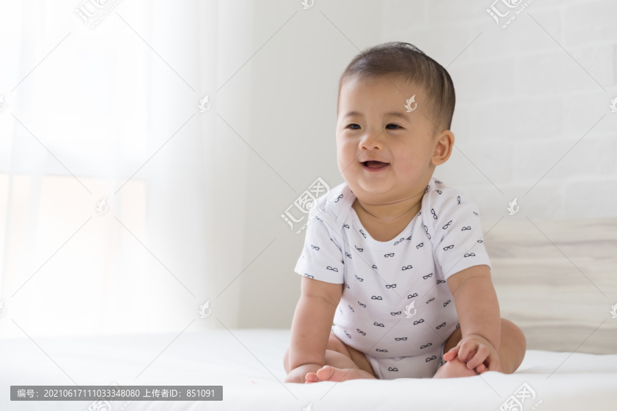 小男孩在卧室的白色床上微笑