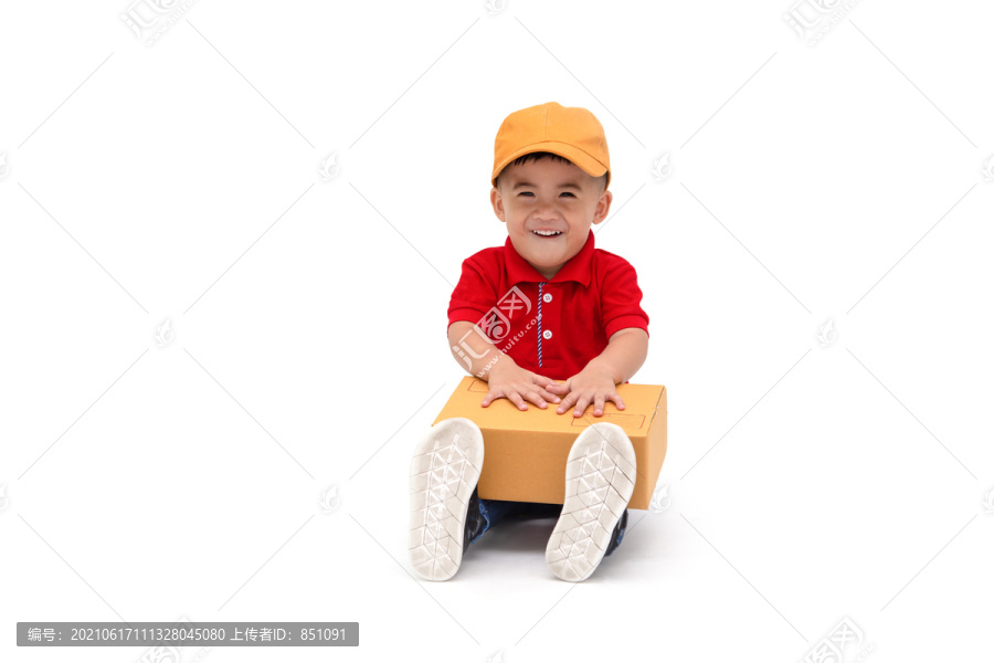 “快乐儿童”亚洲男孩送货员，戴黄色帽子，穿着红色衬衫，坐在白色背景下，包裹邮筒被隔离，两岁一个月大