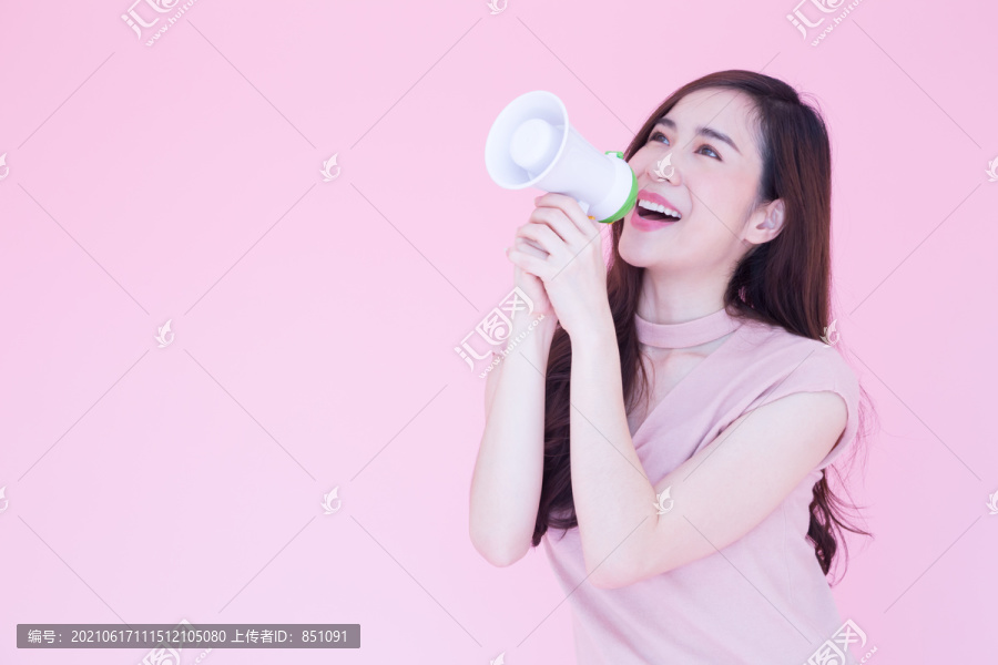 美丽的亚洲年轻女子在情人节上发布消息或用扩音器交流，消息由穿着粉色衬衫和粉色背景的青少年发布