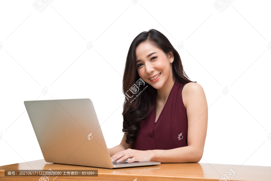 快乐的亚洲年轻女子在白色背景的木桌上使用笔记本电脑
