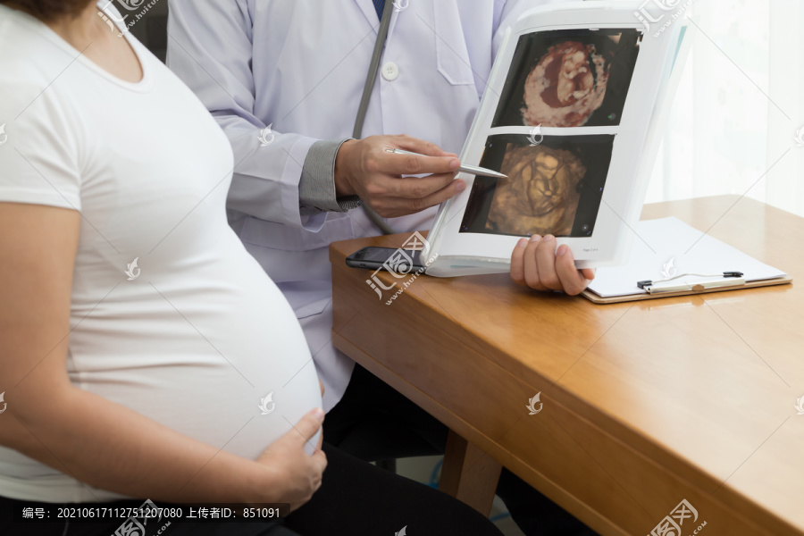 医生手持4D超声图像结果并与孕妇交谈。怀孕期间的概念