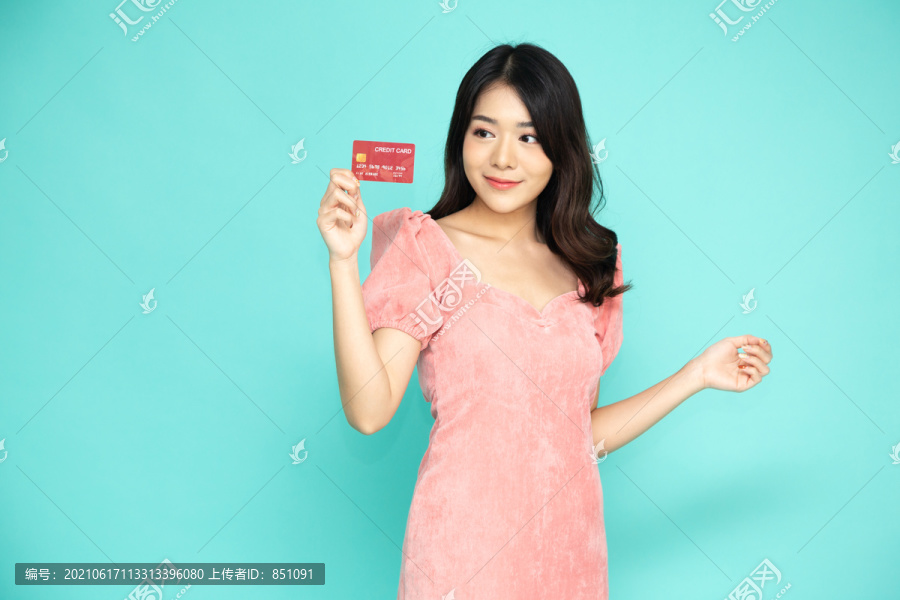 年轻美丽的亚洲女性展示信用卡进行支付或支付在线业务，支付商户或作为商品、持卡人或持卡人的现金预付款