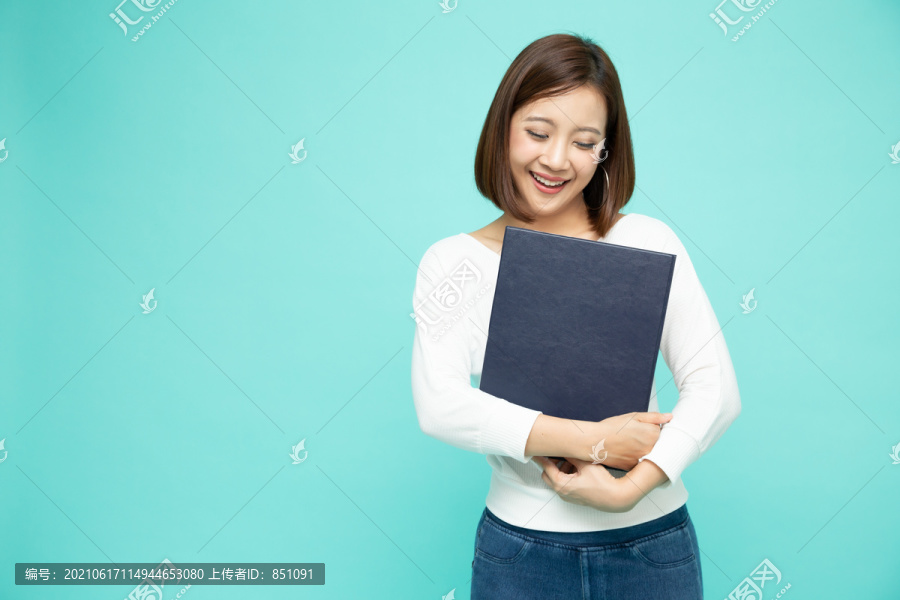 年轻美丽的亚洲女子微笑着，手拿着文件，隔离在绿色背景上