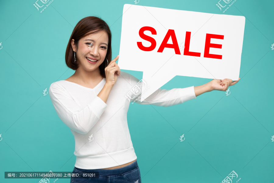 快乐的亚洲女人手里拿着红色销售标志的讲话泡泡，在浅绿色背景上被隔离