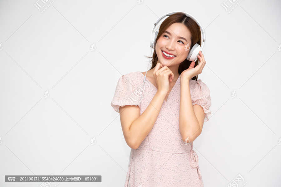 亚洲年轻女子戴着白色背景的耳机听音乐