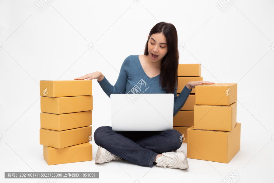 快乐年轻的亚洲女性创业小企业自由职业者，手提电脑，坐在白色背景的地板上，在线营销包装箱交付概念