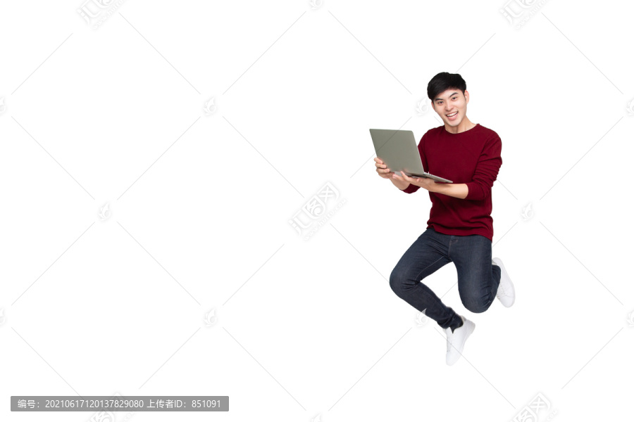 兴奋的亚洲男子在白色背景下跳起，手持笔记本电脑庆祝成功
