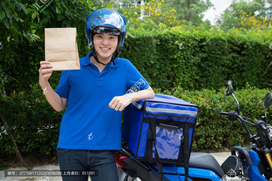 亚洲年轻男子带送货箱、摩托车送食品快递服务理念