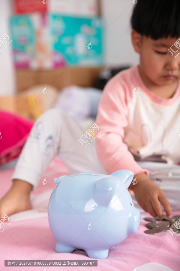 床上孩子身旁的小猪存钱罐