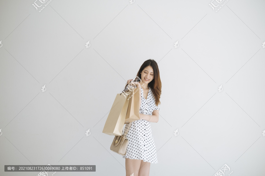 可爱的泰国年轻女子提着购物纸袋。购物后开心地微笑。