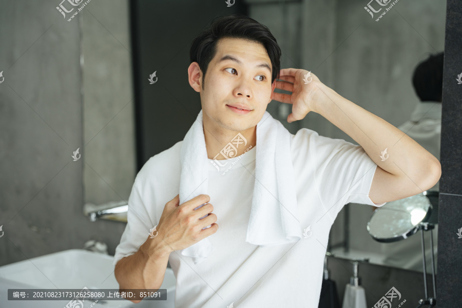 亚洲年轻人的肖像，穿着白衬衫，淋浴后在浴室里用毛巾。