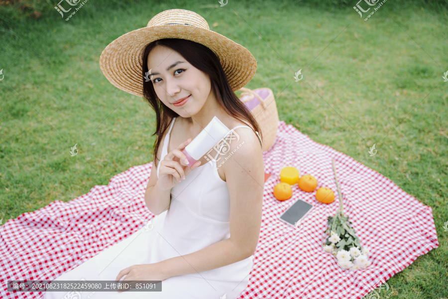 美丽的亚洲旅行家女子，穿着白色连衣裙，在户外公园里喝着白色的乳液。
