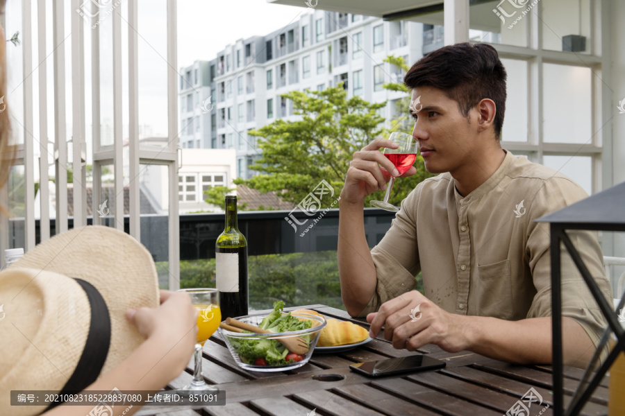 一名亚洲男子在咖啡馆和女友喝红酒。