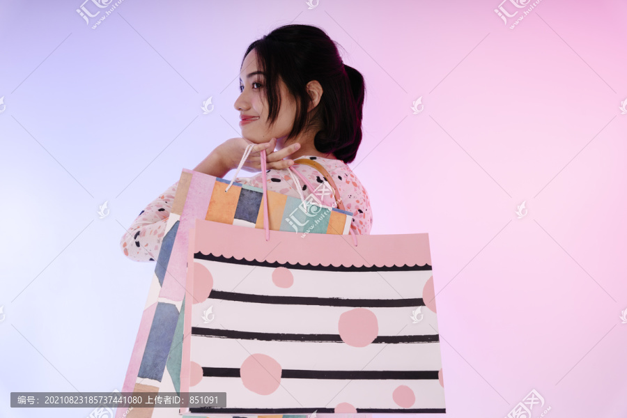 穿着考究的年轻亚洲女子手持购物纸袋的肖像。模型设计。