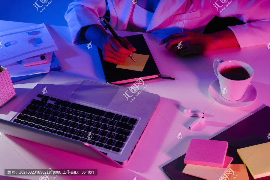 俯视图-商务女性工作台，配有霓虹灯下的笔记本电脑、书籍、咖啡和电话。