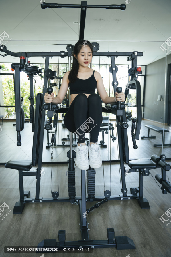 健康的亚洲女性在健身房用健身机锻炼。
