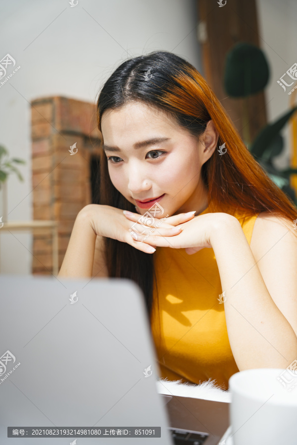 美丽的亚洲年轻女子专注地看着笔记本电脑。