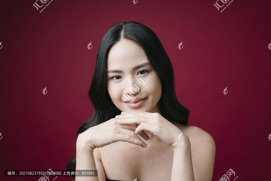 美丽的年轻亚洲女性肖像，皮肤干净完美，自然妆容，红色背景。