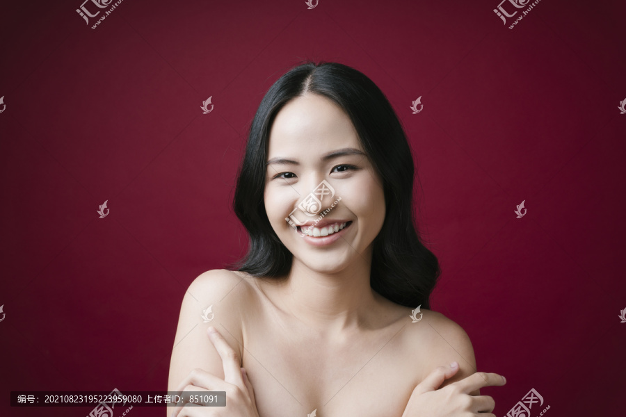 美丽的亚洲年轻女子的肖像，黑色头发，完美的皮肤，干净的红色背景。