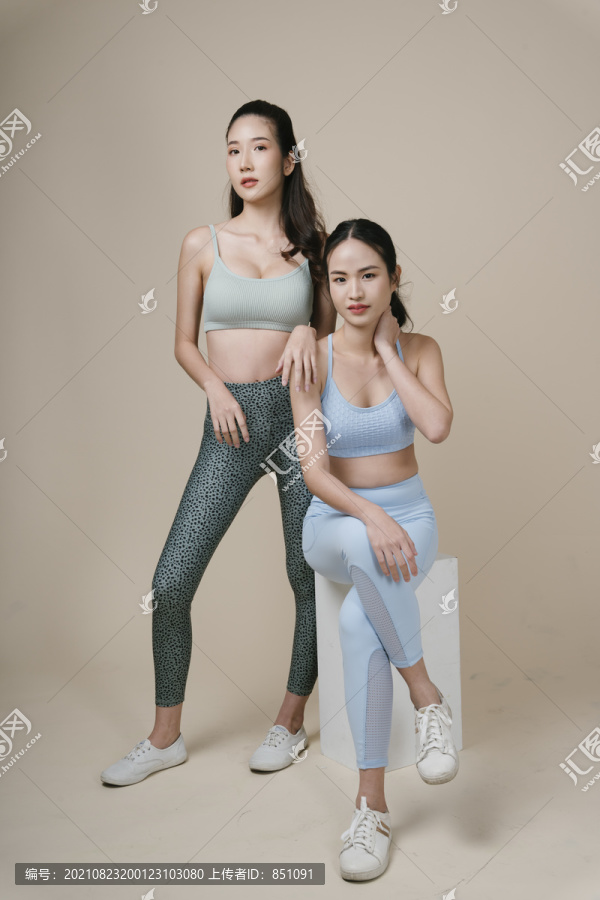 在摄影棚灯光下，两位亚洲运动女性穿着运动胸罩的运动员肖像。