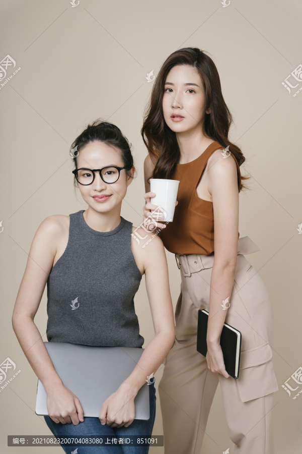两位穿着休闲衬衫的亚洲女商人站在一起的肖像。