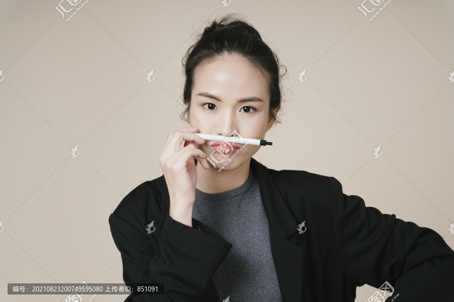 亚洲女商人穿着米色背景的黑色夹克的肖像。