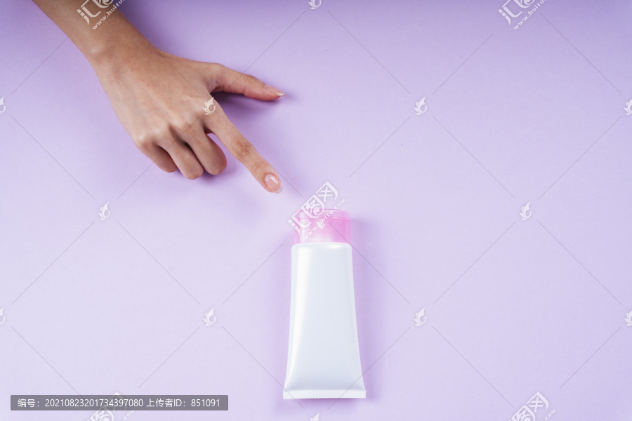 女士用手指着洗液管，在紫色背景上模拟和复制空间。