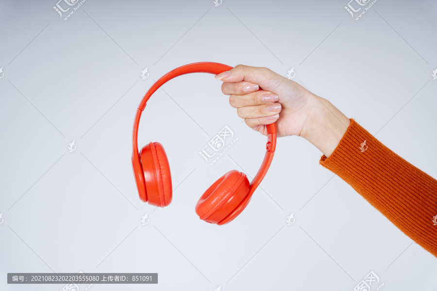手持红色耳机的女性手与白色背景隔离。