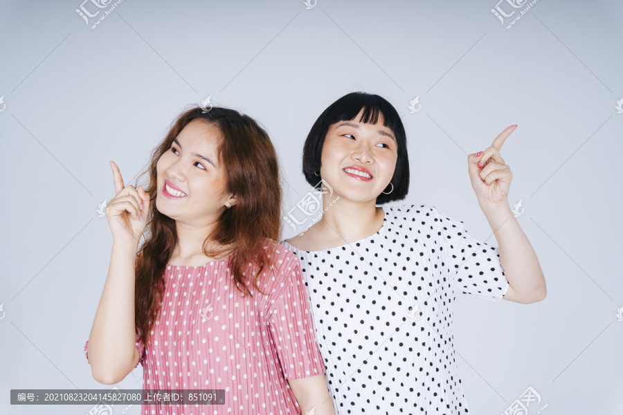 两位年轻亚洲女性指着产品的空白处的肖像。