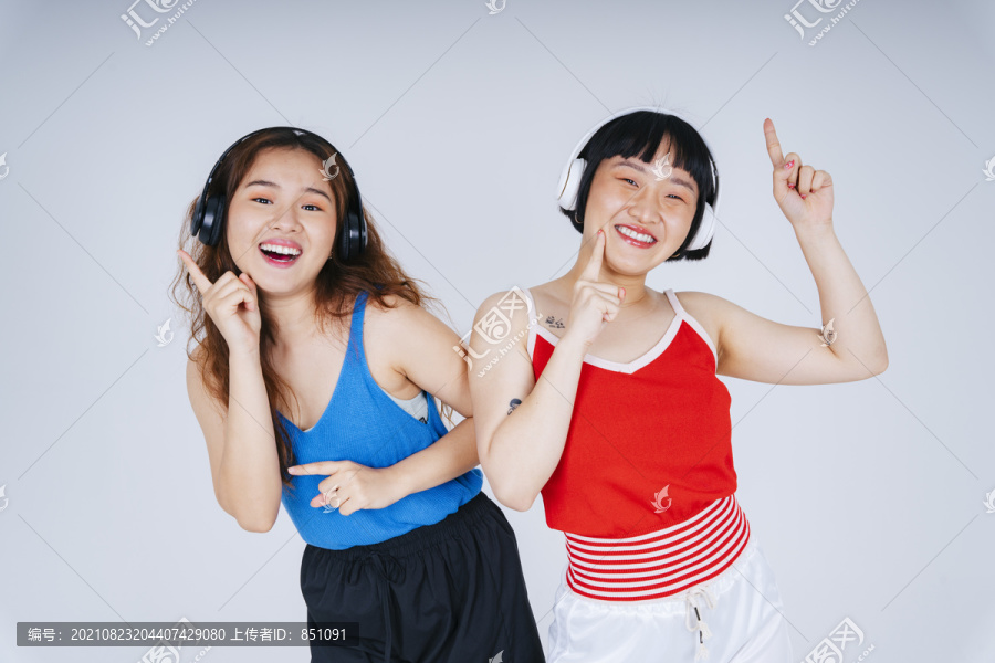 两位年轻亚洲女性的肖像画，在白色背景下欣赏音乐和舞蹈。