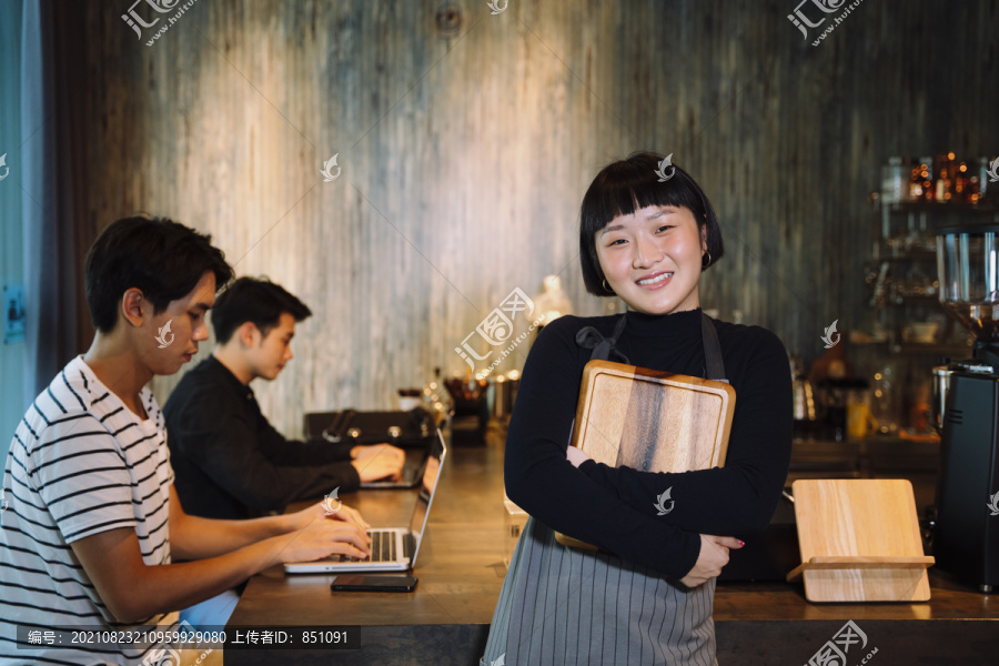 在自助餐厅拿着木制托盘的年轻亚洲短发女服务员的肖像。