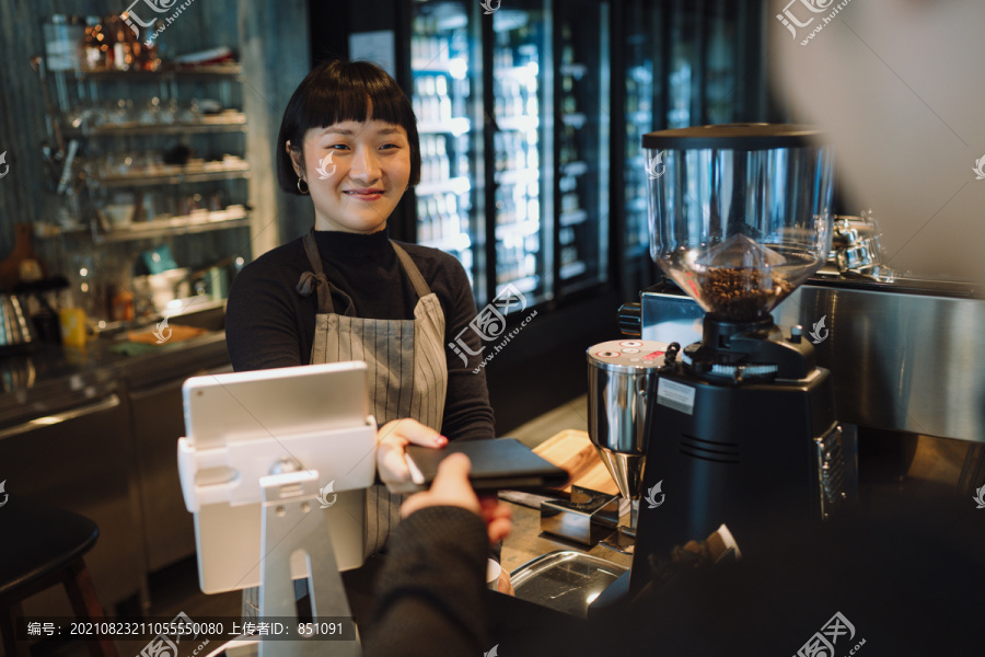 亚洲短发女咖啡师给顾客二维码付账。