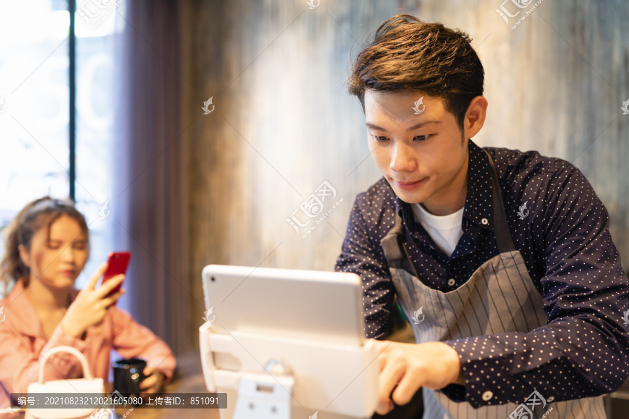 亚洲咖啡师在笔记本电脑上的数字菜单中寻找食物。