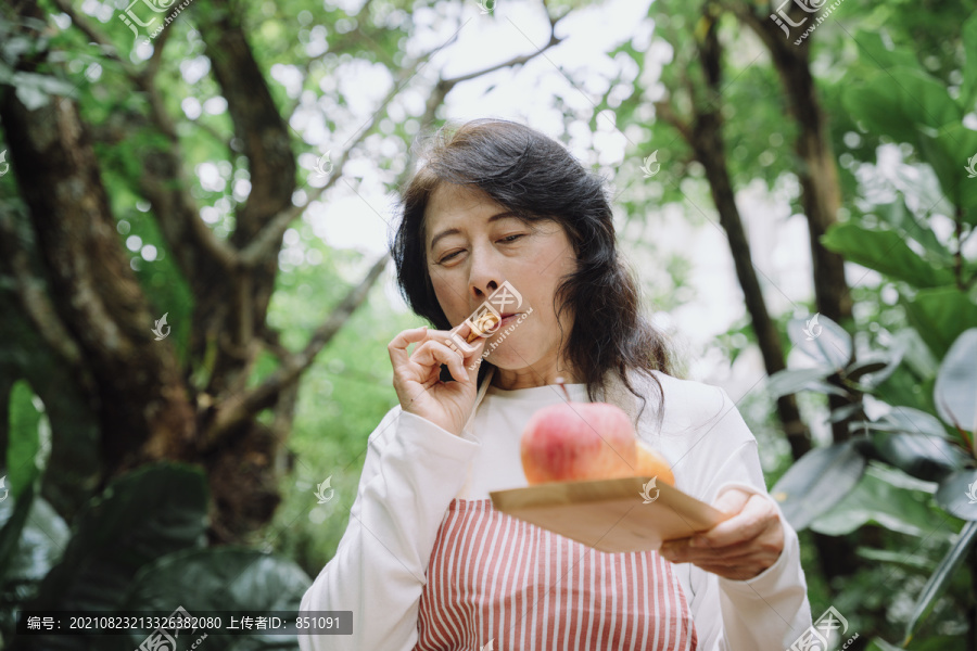 早餐吃饼干和苹果的亚洲老太太。