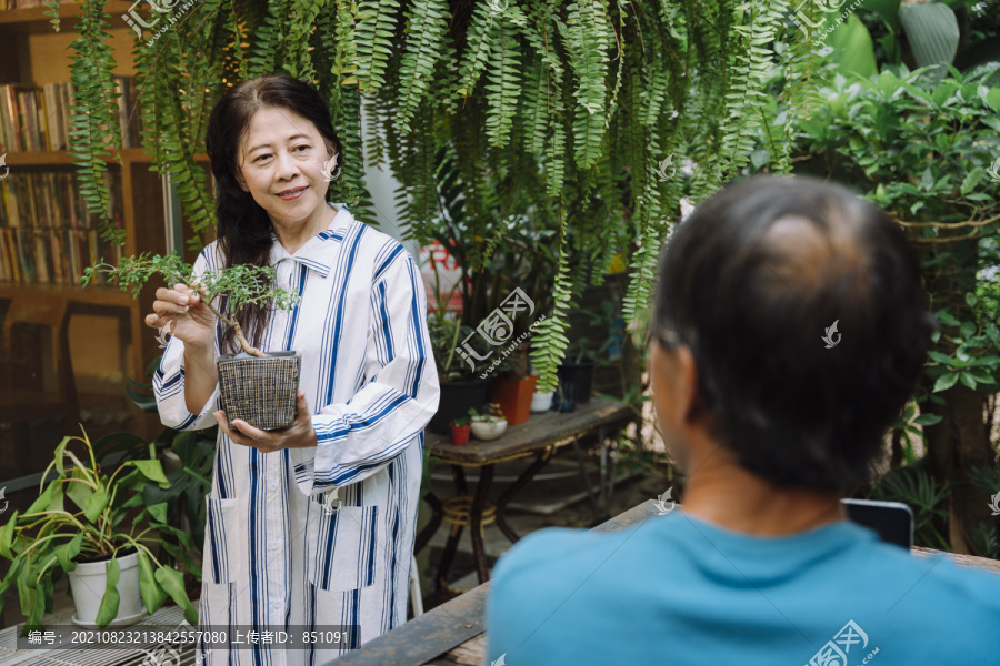 和丈夫在花园里照料植物的亚洲老妇人。