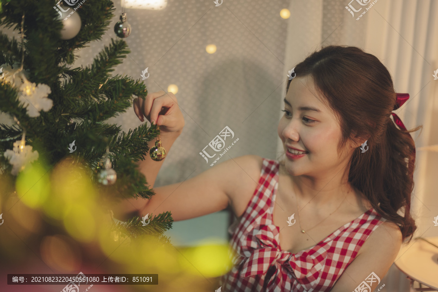 美丽的亚洲年轻女子黑头发在派对上装饰圣诞树。