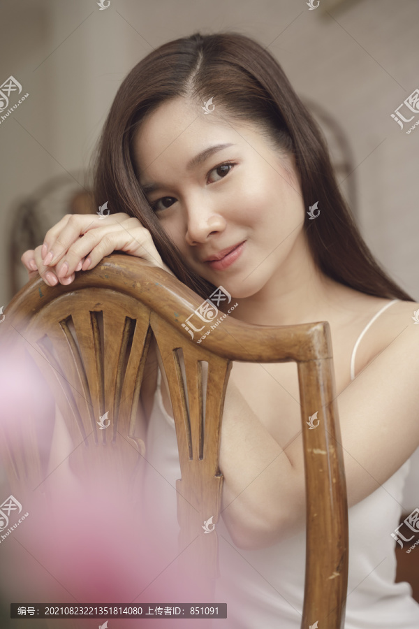 年轻亚洲美女坐在木椅上的特写肖像。