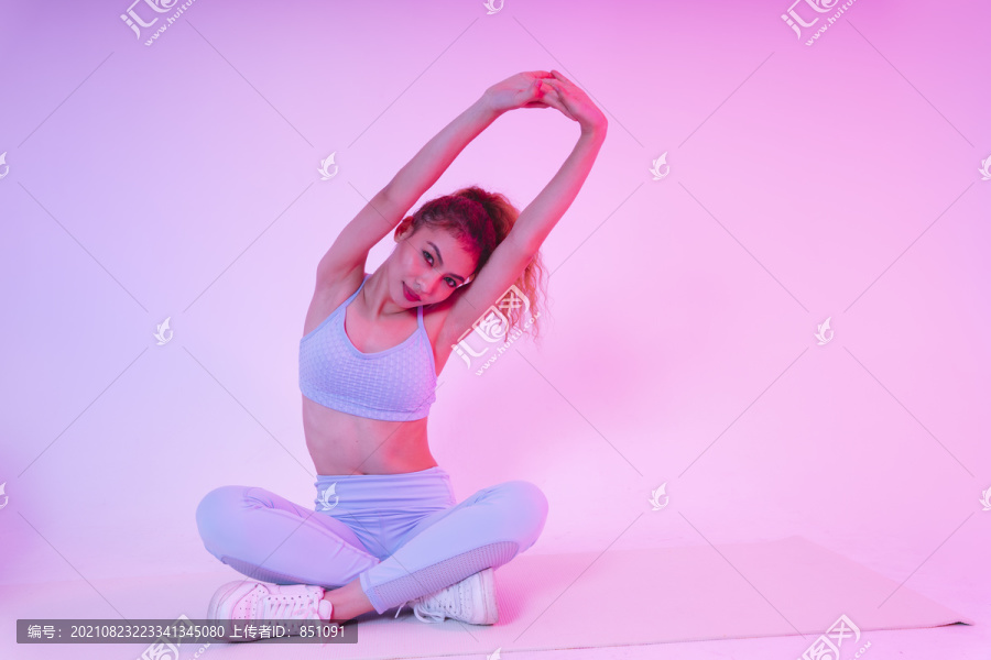 年轻的亚洲健康女孩在做瑜伽，在空中伸展手臂。
