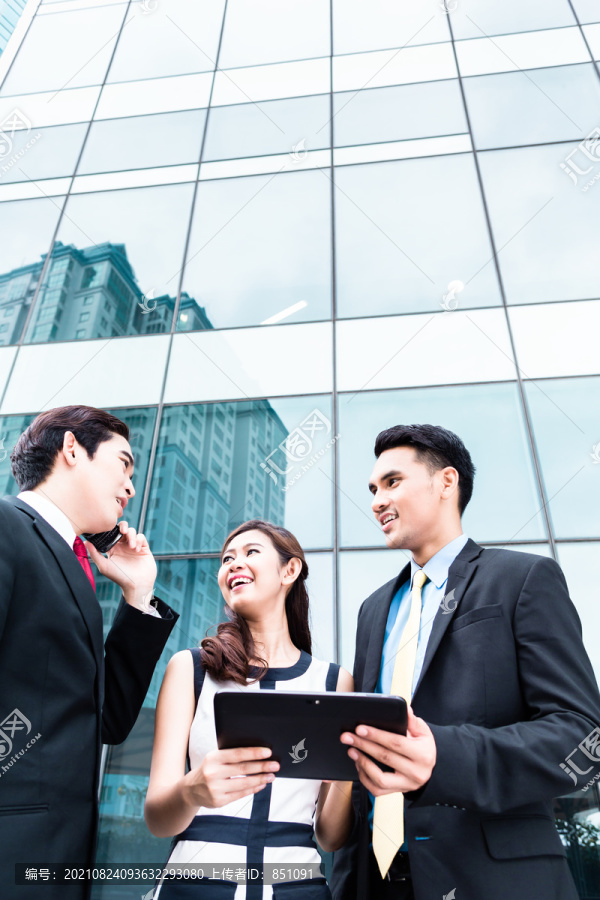 亚洲商界女性和男性在户外使用平板电脑和手机
