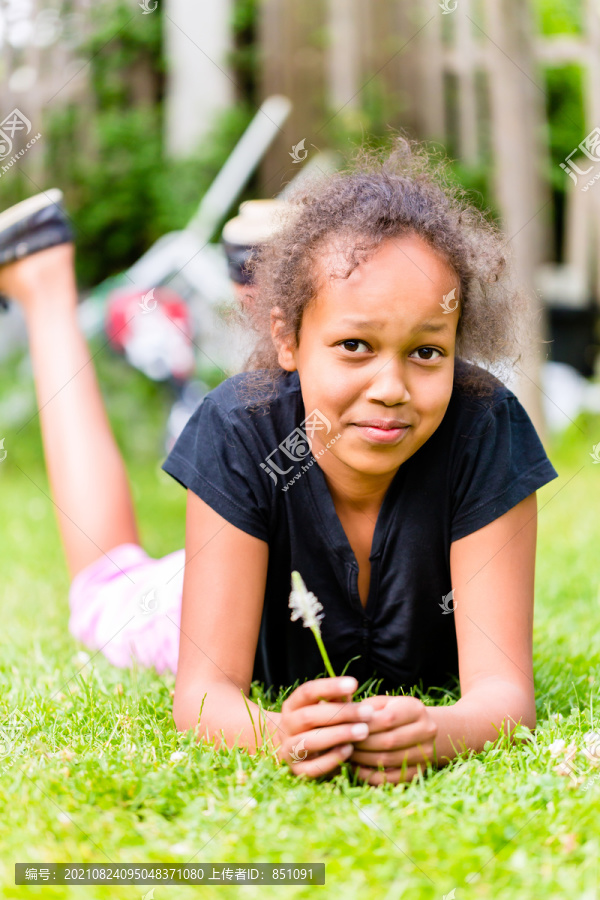 夏天，一个带着草叶躺在草地上的黑女孩