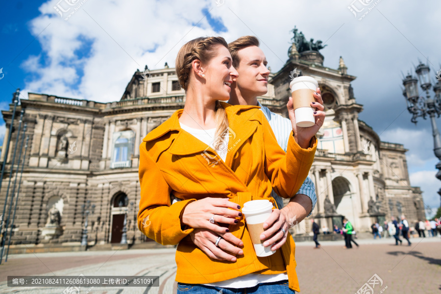 德累斯顿Semperoper的一对旅游夫妇带着咖啡散步，准备外卖