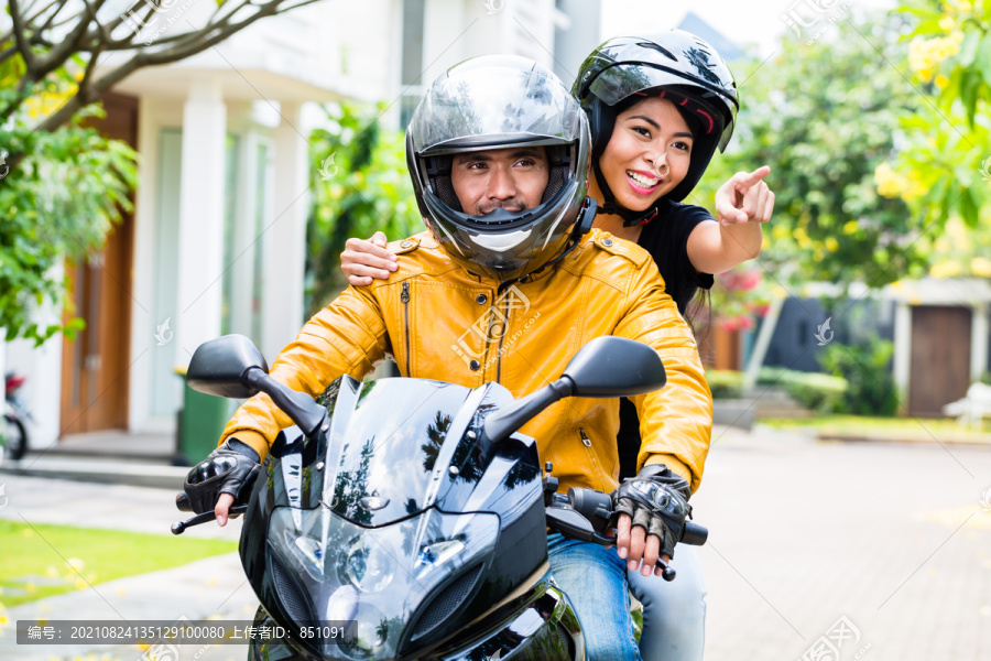 一对戴着头盔的夫妇骑着摩托车，妻子坐在丈夫后面