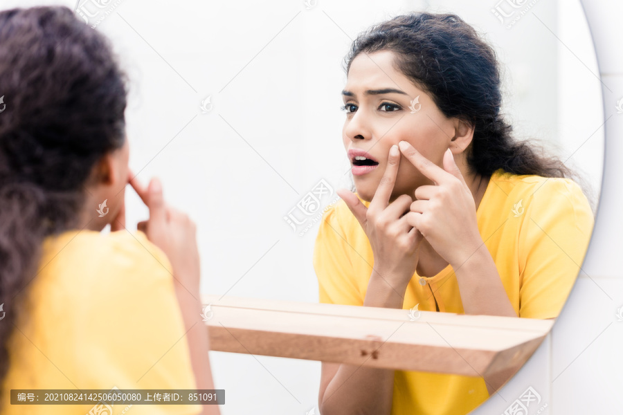 一个女人在镜子里挤痘痘的特写镜头