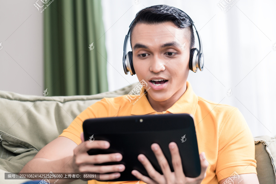 一个年轻人在数字平板电脑上看电影的画像