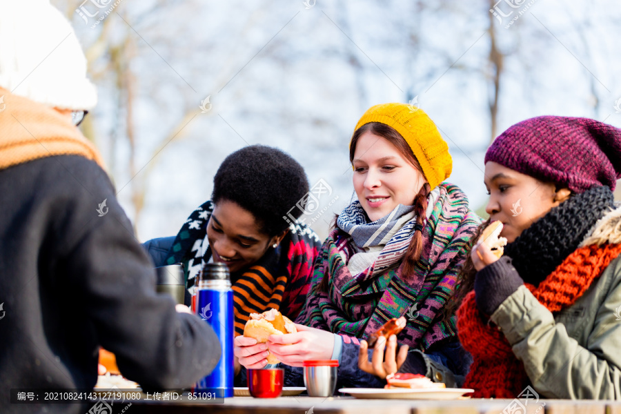 在寒冷的冬天，年轻的朋友们在公园户外野餐时聊天