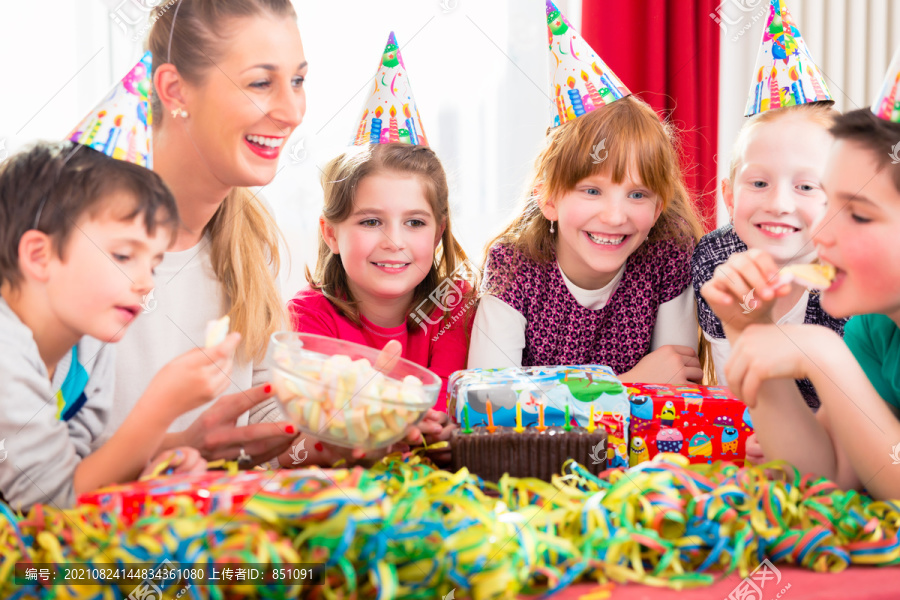 孩子们在生日派对上戴着派对帽啃糖果